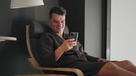 Ein-Glücklicher,-Entspannter-Mann-Chattet-Online-Per-Smartphone,-Sendet-Eine-Nachricht-Und-Lächelt-Im-Liegestuhl